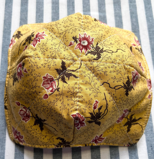 Shows the underside of a golden yellow cotton print bowl cozy for holding your hot soup bowl. it has a small vine print with reddish pink flowers. (etsy image id: 6771741625)