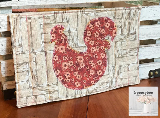 Mug rug used for placing your drink on along with a pastry.  has floral applique of a chicken  and the background is a rustic wood print on 100% cotton. Lightly quilted. (etsy image id: 6528157454)